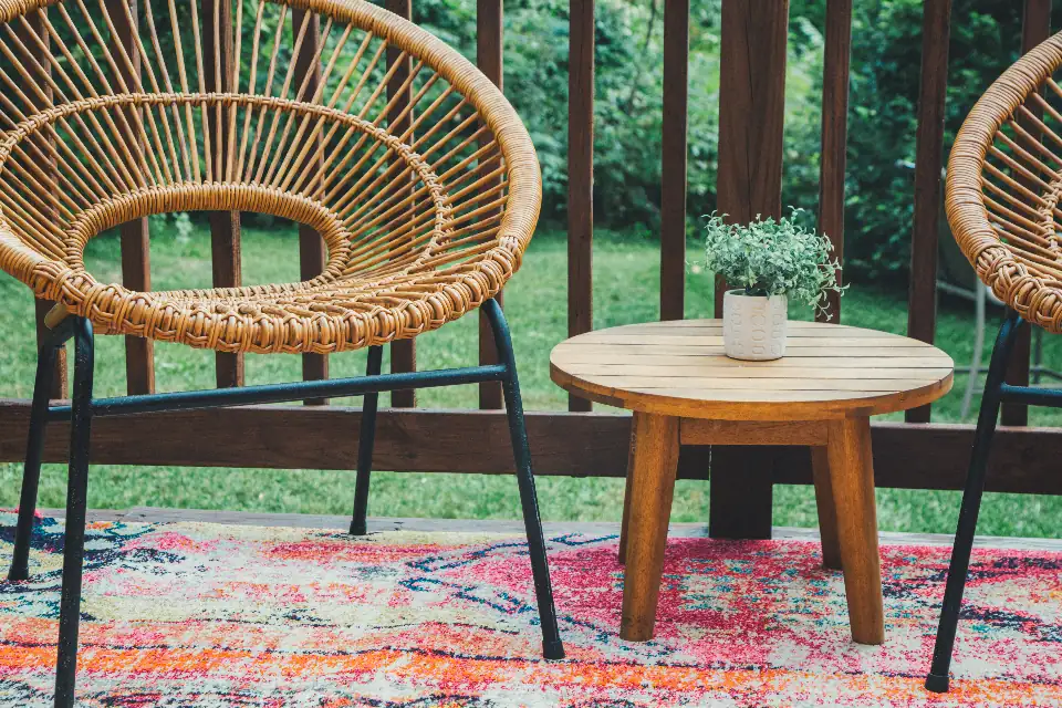 Wicker chairs and a small table on a swept porch